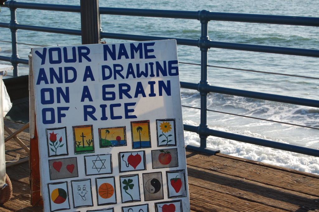 Artist sign advertising name and drawing on grain of rice - Santa Monica Pier for Families - Exploring Through Life