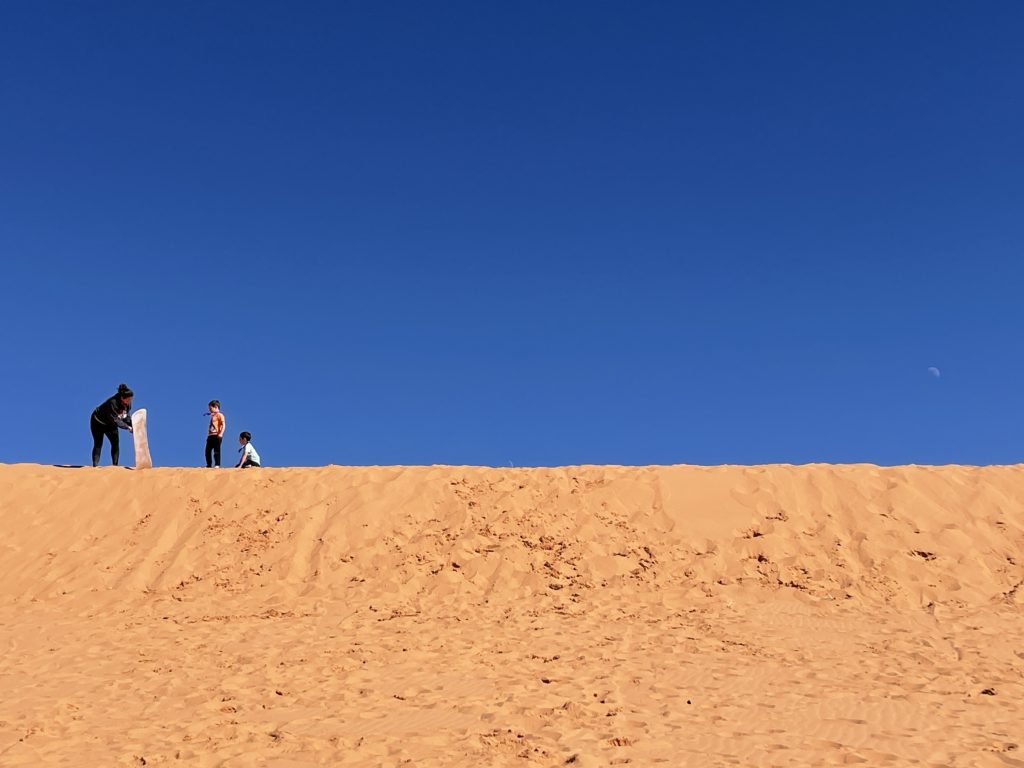Sandboarding at Coral Sand Dunes State Park is a great day trip to take from St. George, Utah, with your kids. - Exploring Through Life